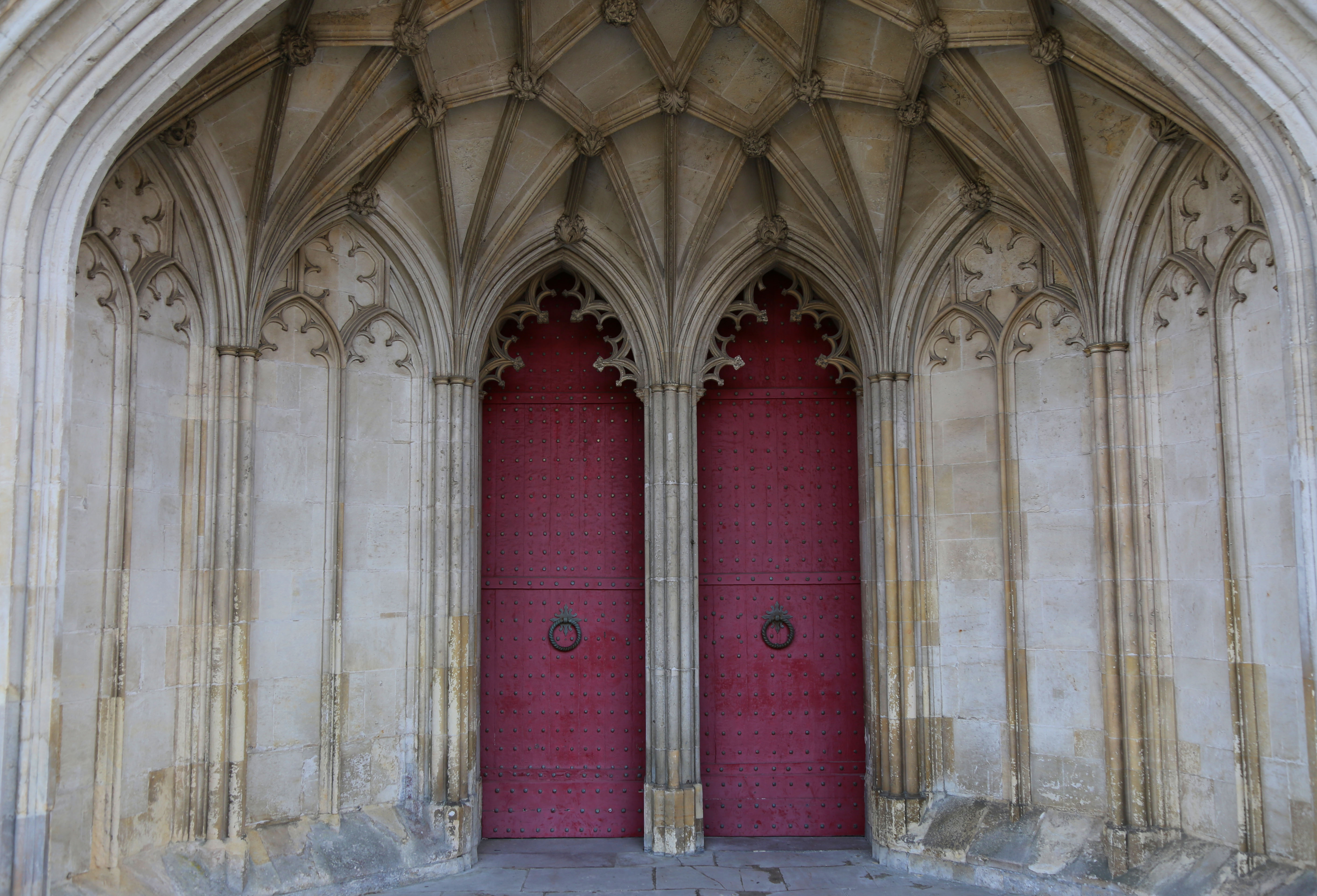 Two aged red doors that lead into Winchester Cathedral