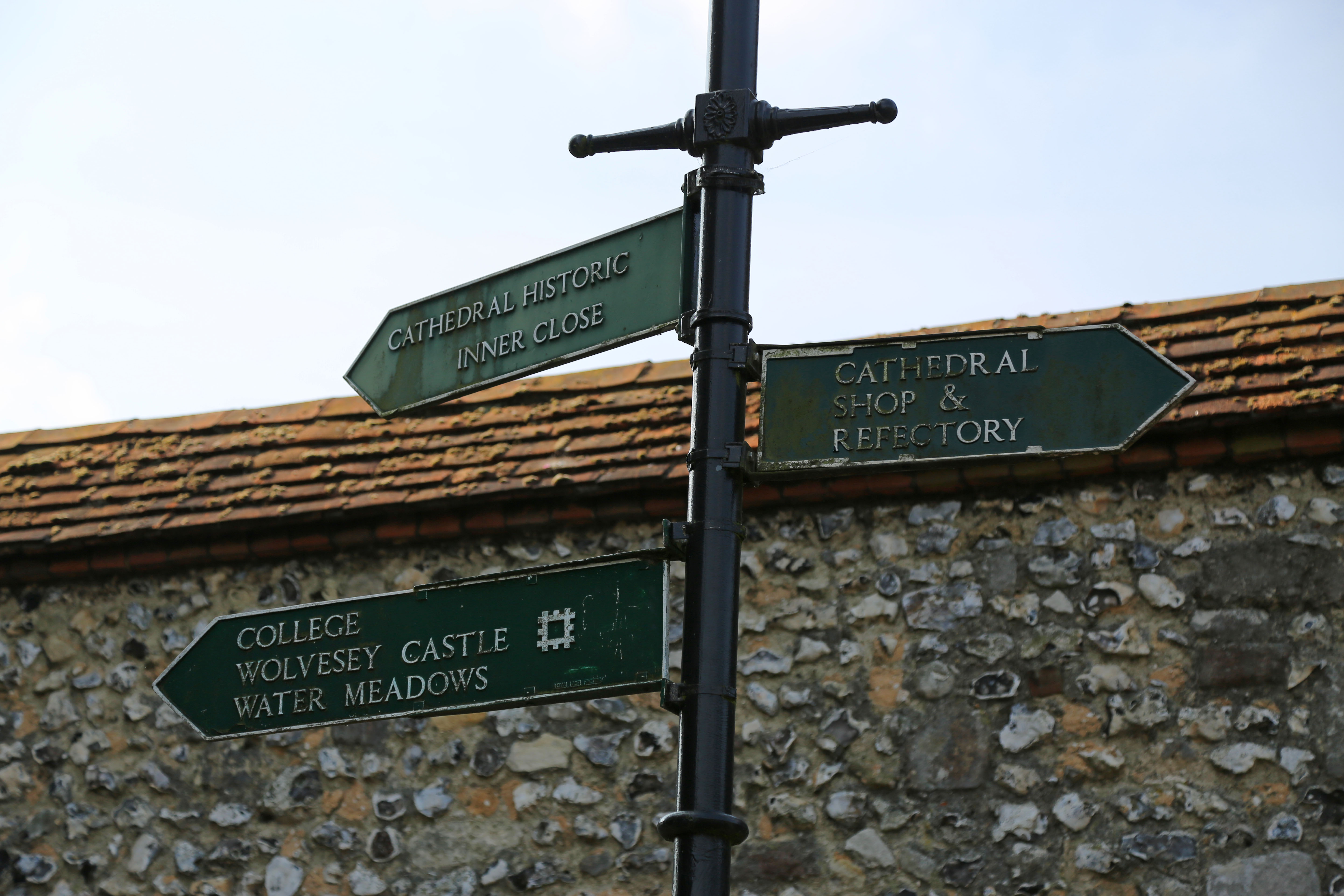 Three green signs pointing to various places around the catheral.