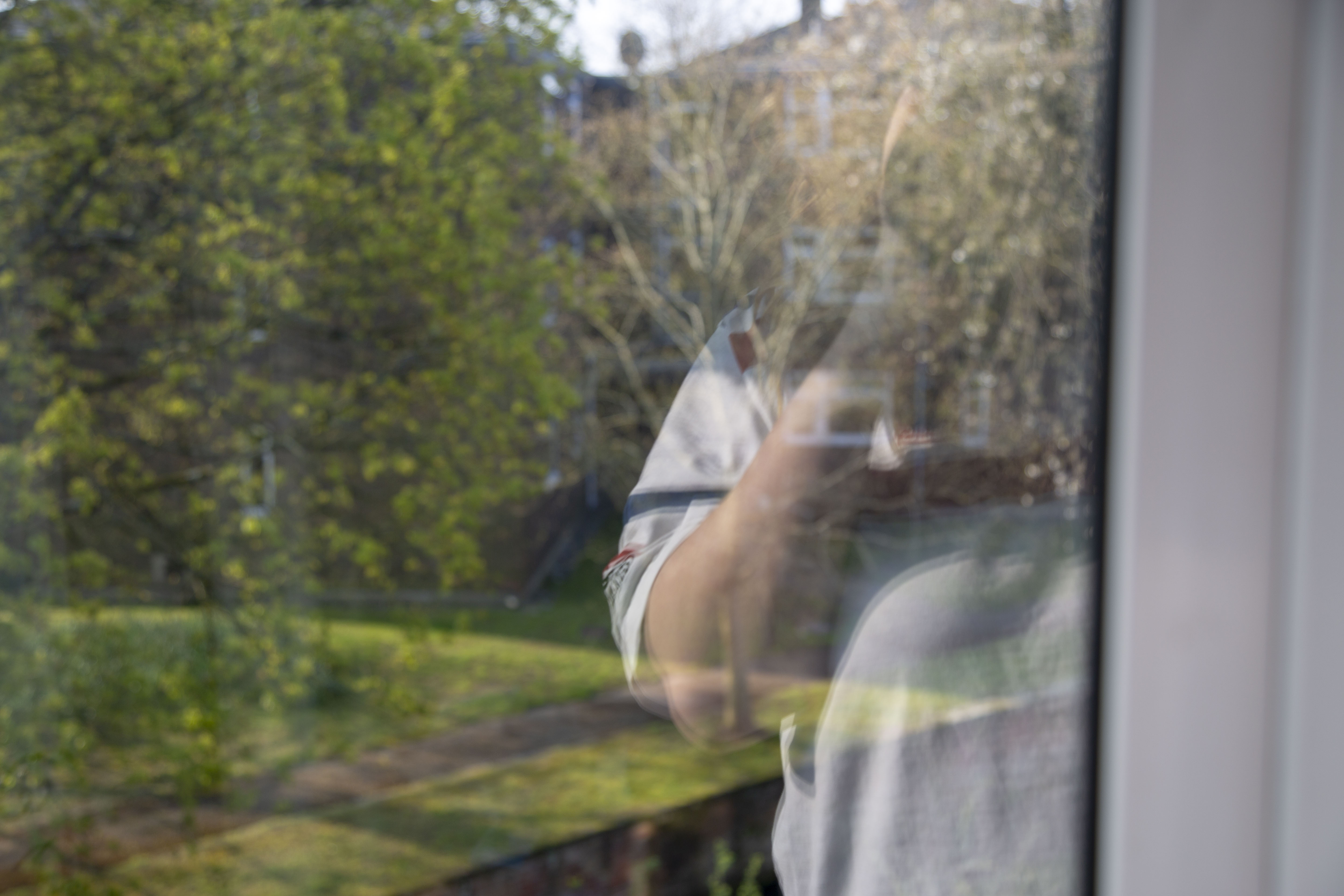 A picture of a window - in the background are trees, and in the foreground is Rosie's torso in a white pajama top