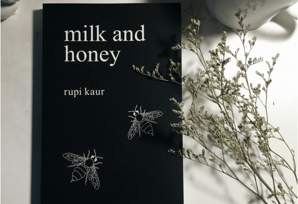 Black cover of Rupi Kaur's 'Milk & Honey' with some wildflowers