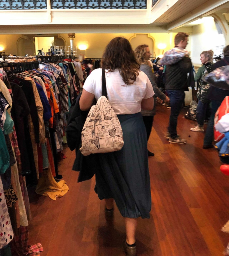 Rosie walking away, dressed in a teal midi skirt and white tee