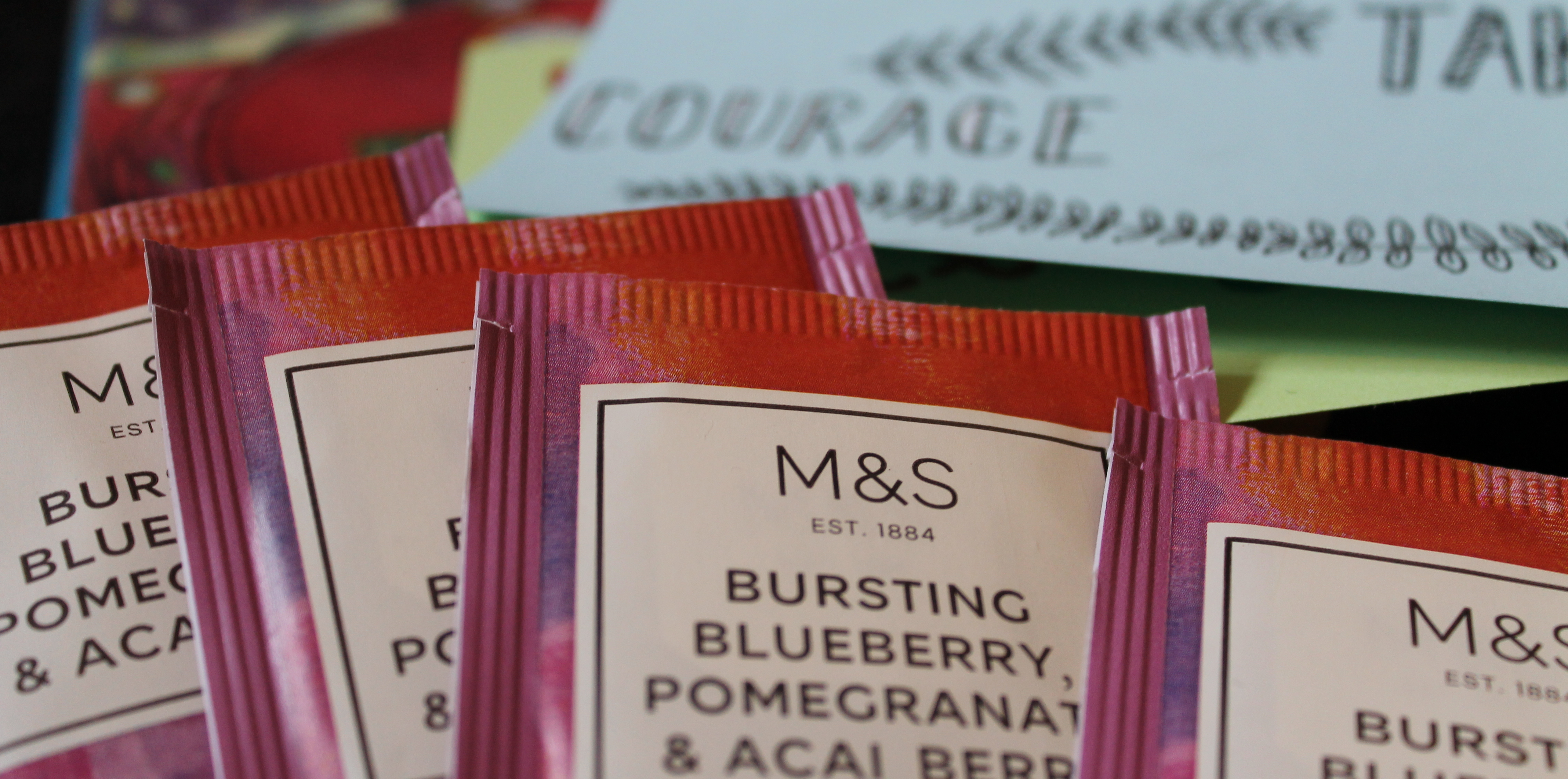 Pink and red packets of tea, with blue paper in the background