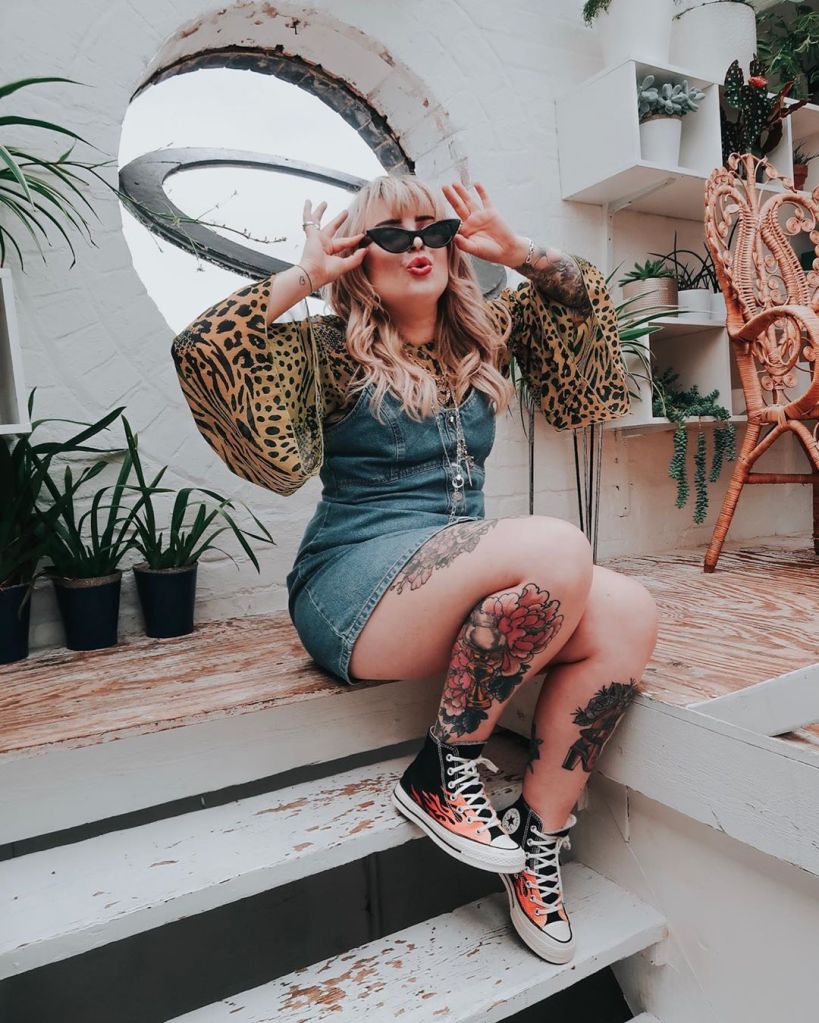 Helen wearing a denim mini dress and black sunglasses