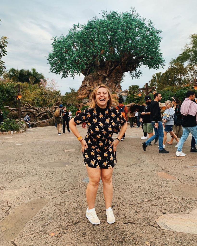 Hannah in a black and orange ensemble, jumping in from of the Tree of Life at Disney's Animal Kingdom
