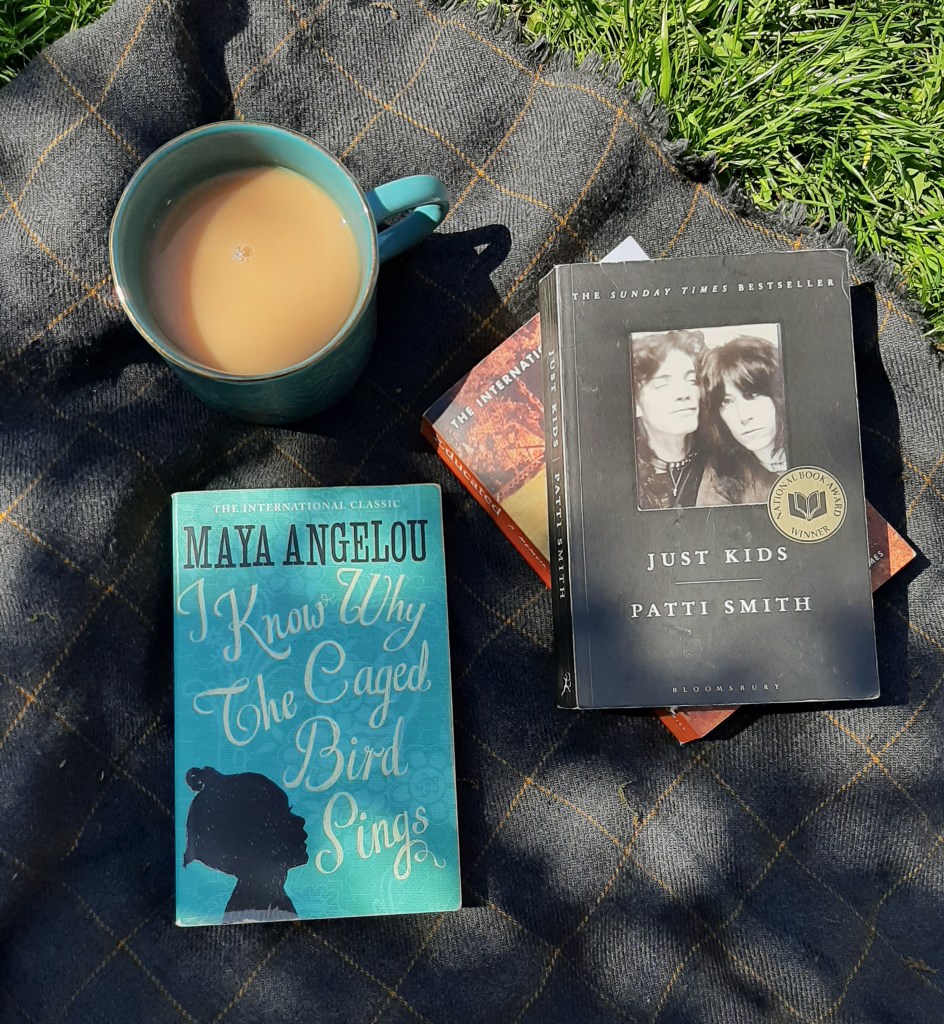 Cup of tea and three books on a grey blanket