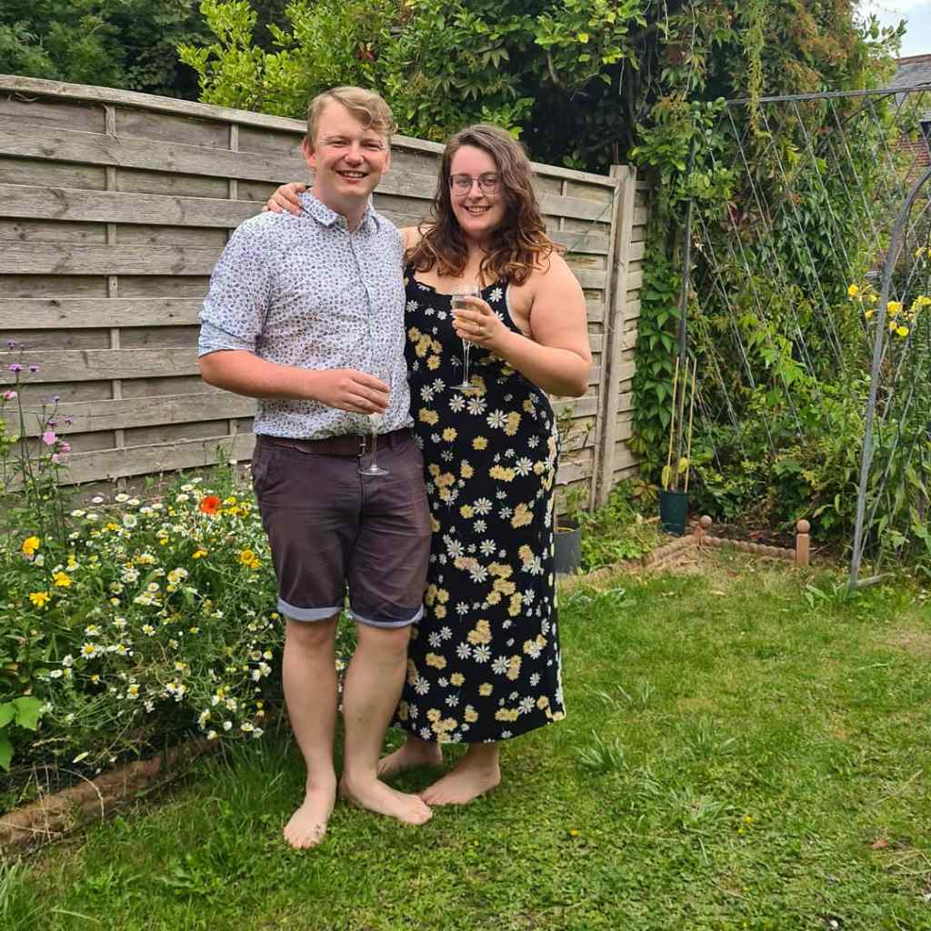 Rory and Rosie stood next to each other in the garden - thy are both holding glasses of champagne.