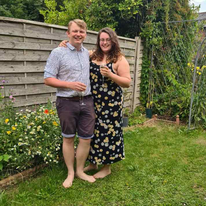 Rory and Rosie stood next to each other in the garden - thy are both holding glasses of champagne.