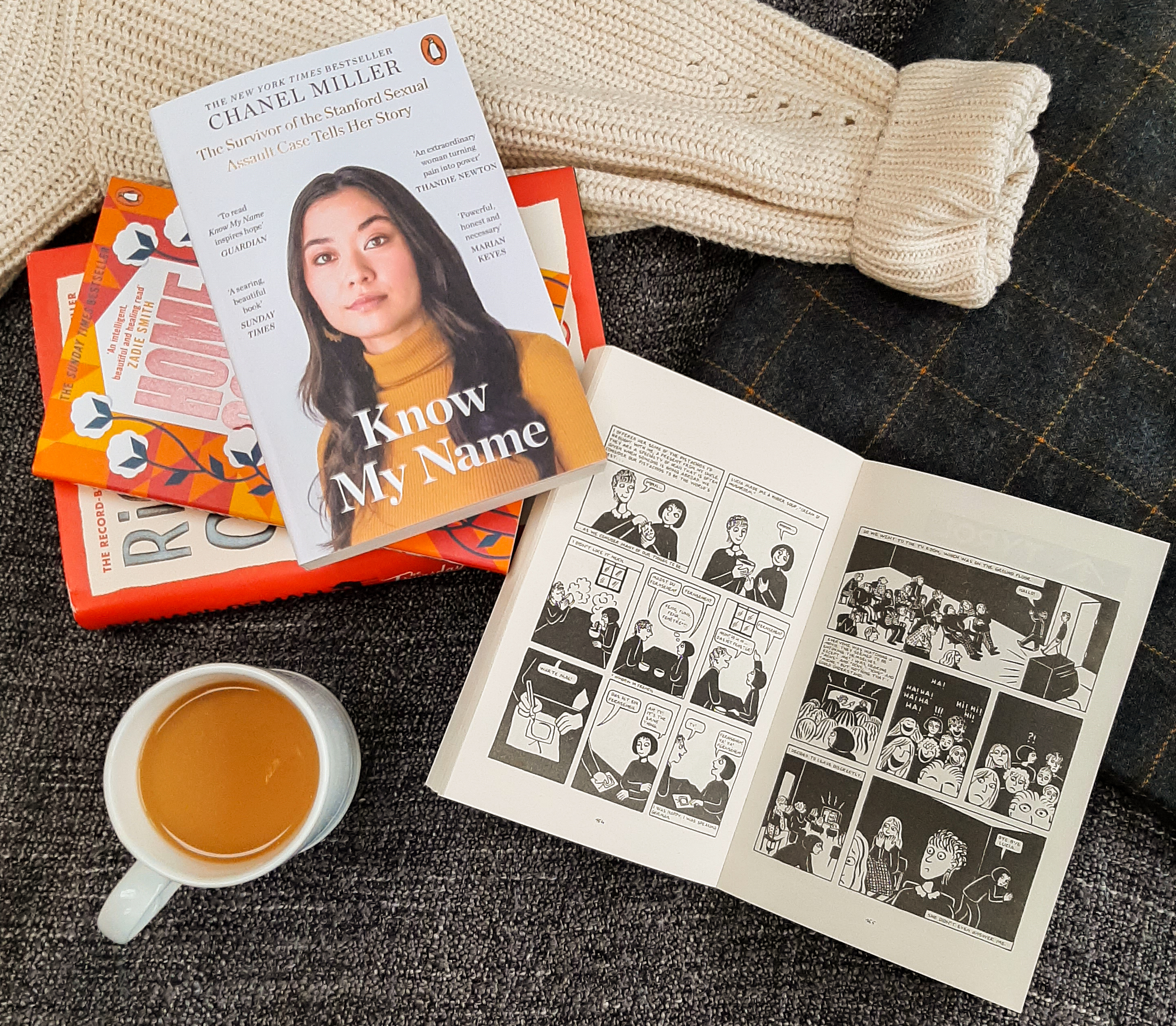 Cup of tea in a white mug, bottom left. Top right, a stack of orange and white books.