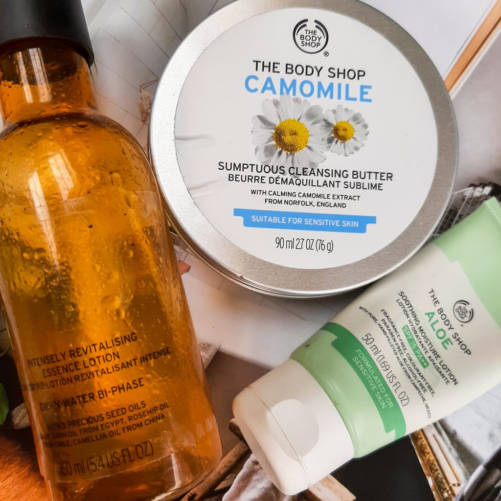 l-r; an amber coloured bottle of Bi-Phase Lotion, a silver and white tin of Camomile Balm, and a white and green tube of Aloe Lotion