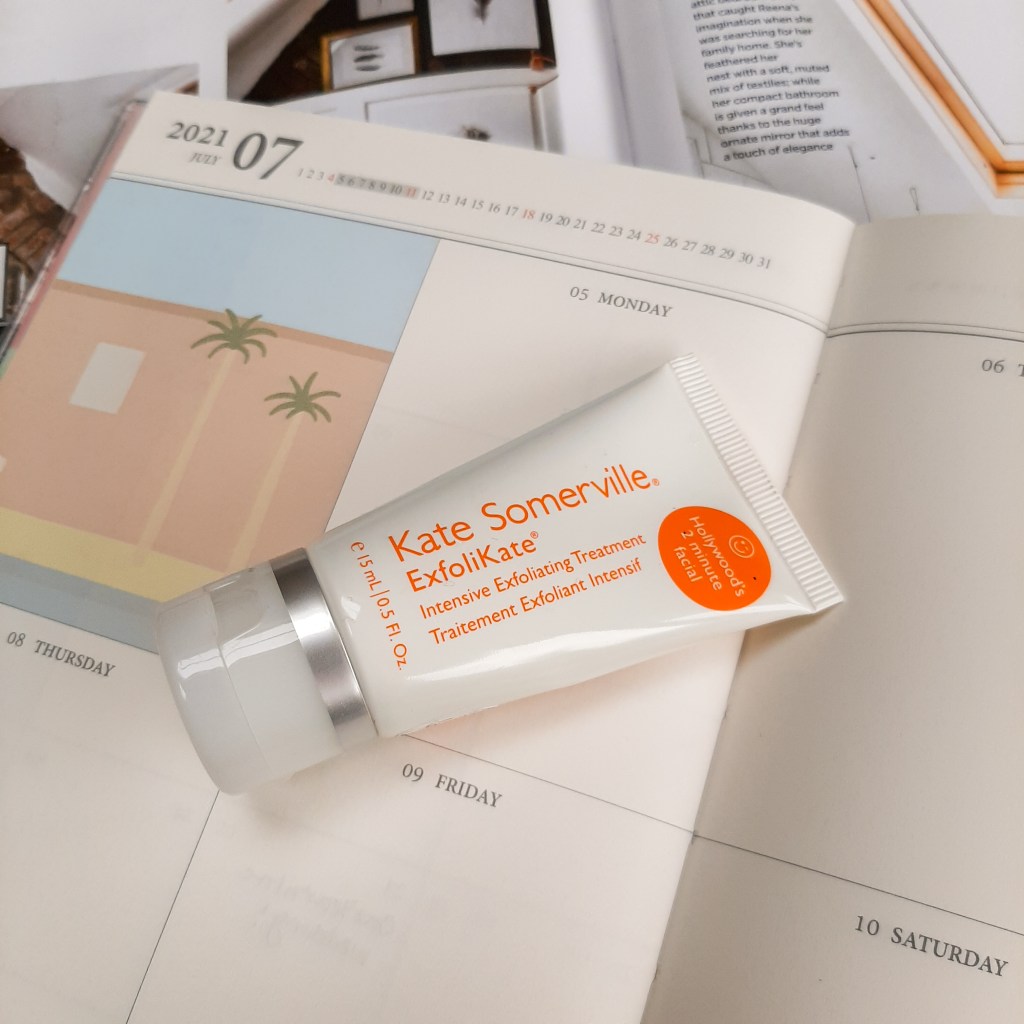 A white tube of Exfolikate on a cream and white background of a diary and magazine