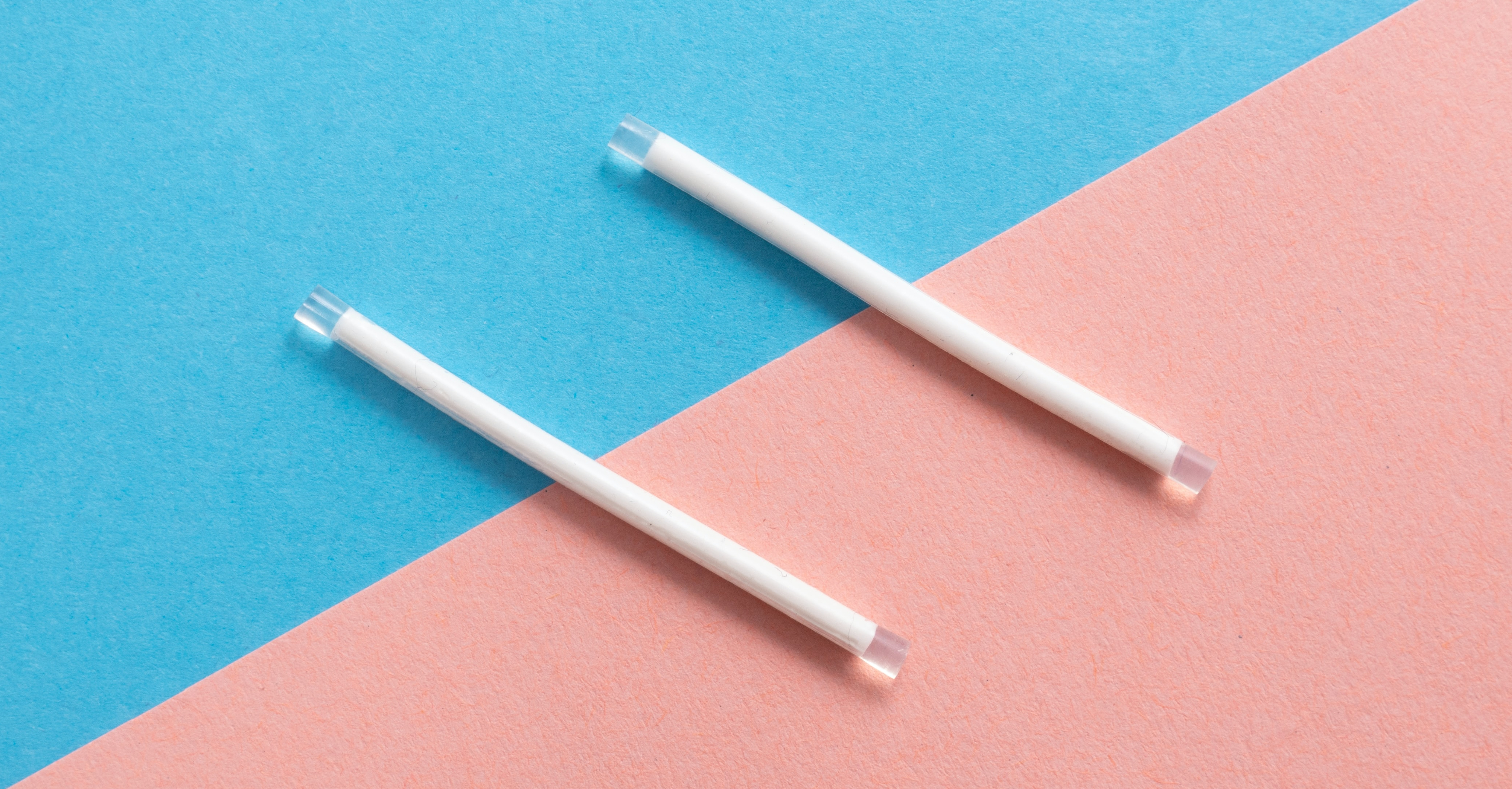 Two white implant rods on a blue and pink background