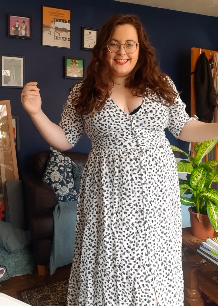 Rosie dressed in a white dress with black and grey spots. She is smiling at the camera.