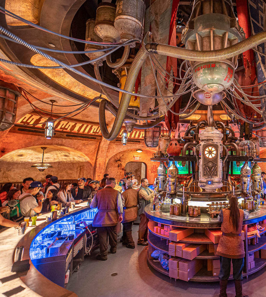 A picture of the mechanical themed bar at Oga's Cantina. Staff work a bar within a circle, and the guests are outside the circle.