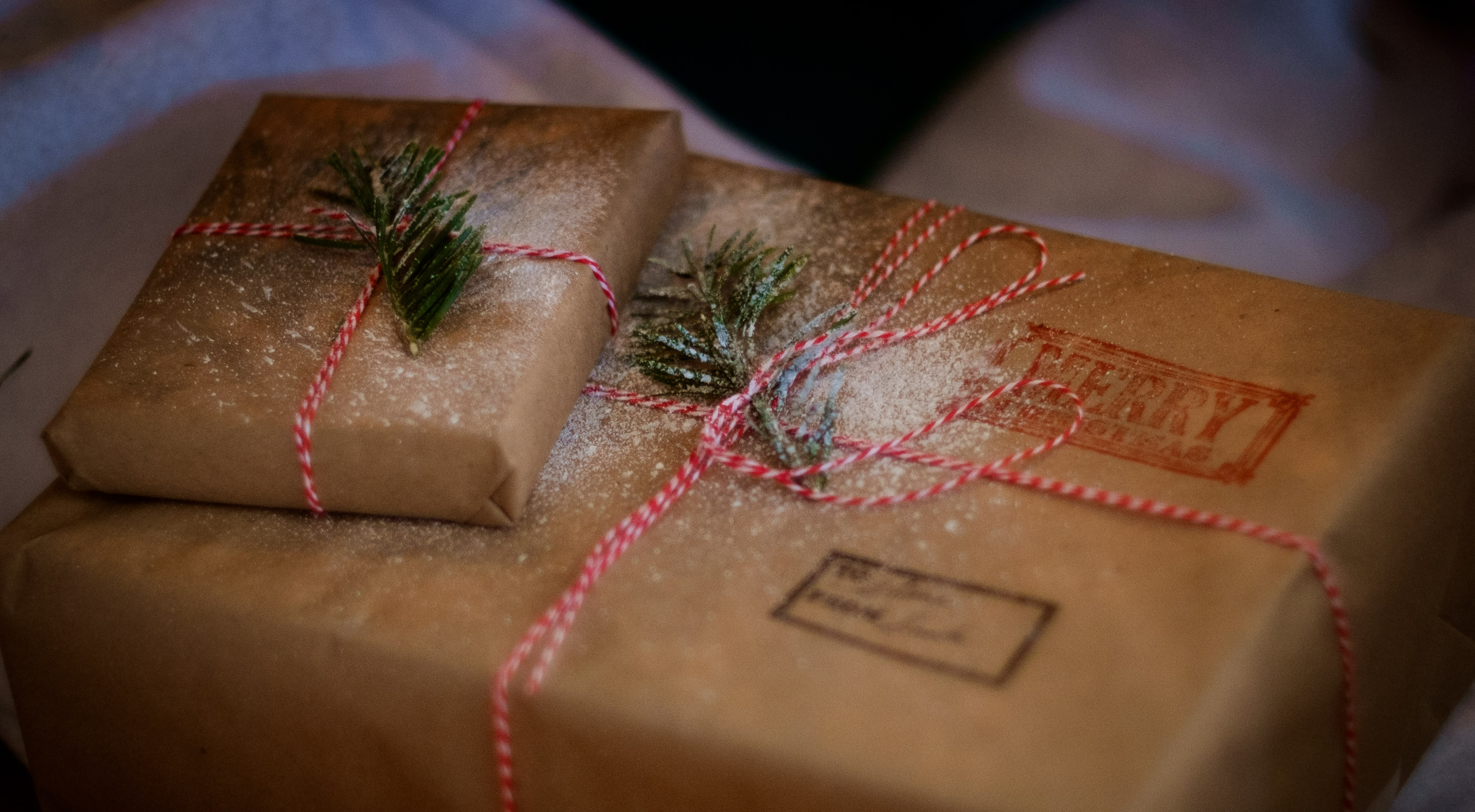 Two brown wrapped parcels with red and white string, and a sprinkle of snow.
