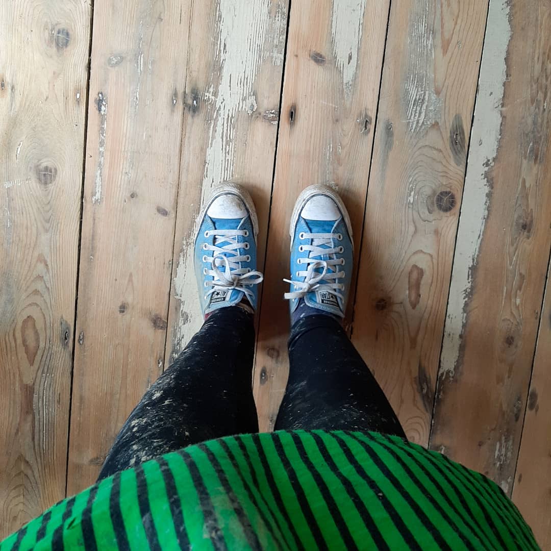An image of Rosie's Blue Converse on freshly sanded floors. Her leggings are black and filthy!