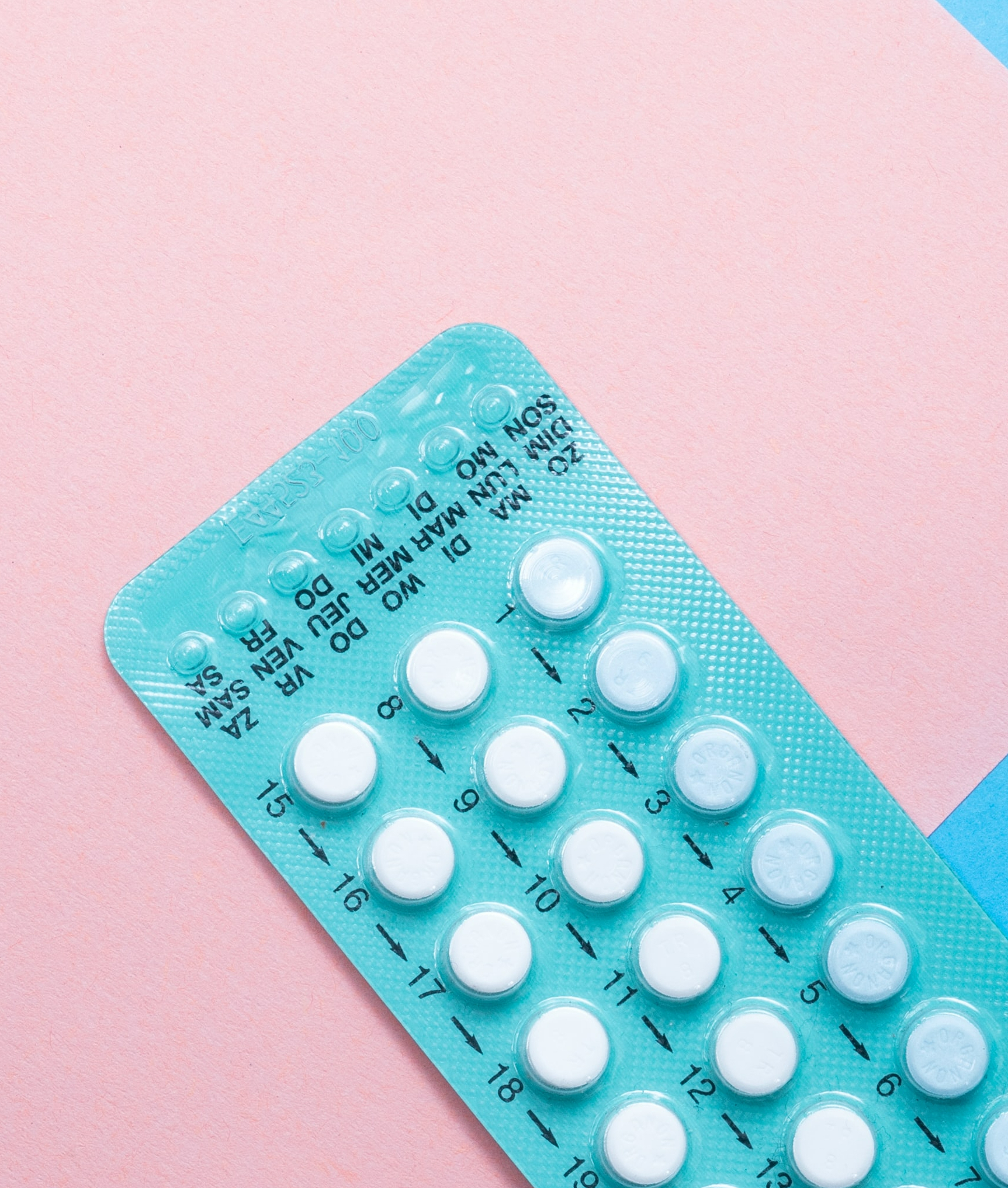 A light blue sleeve of white tablets, numbered. The background is pink and blue.