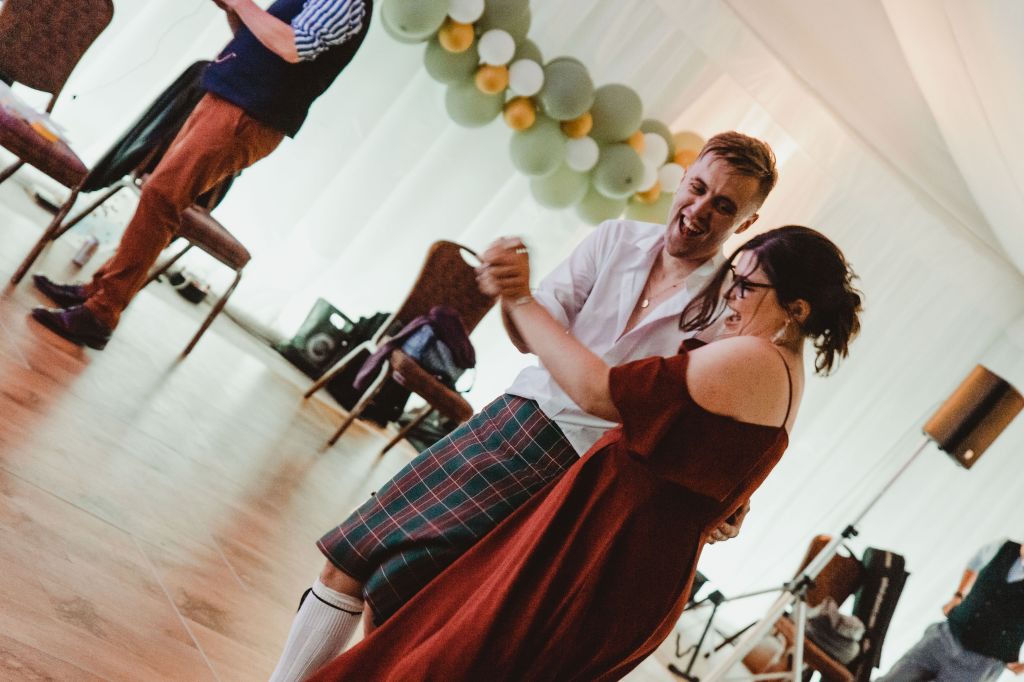 A blurry image of a groomsman and a bridesmaid dancing together. They are both grinning in joy.