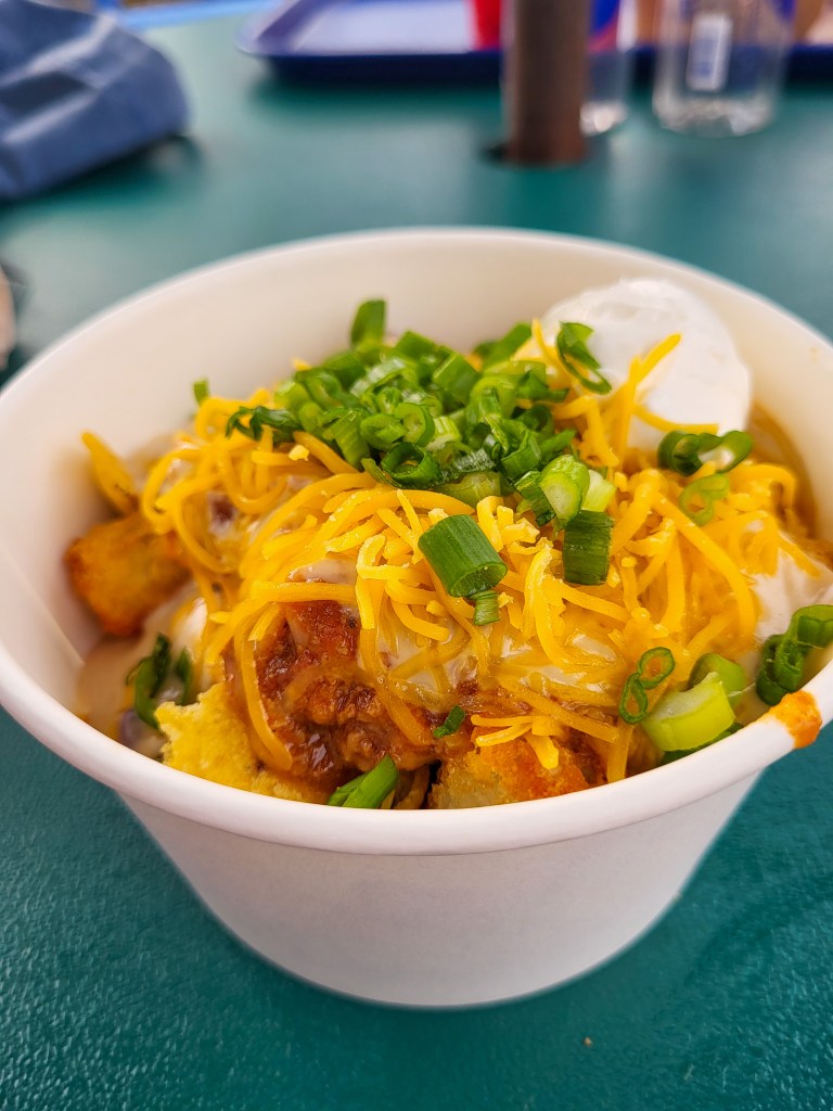 An image of totchos. Potato barrels, covered in cheese, sour cream, and green onions. 
