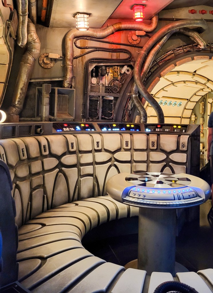 The inside of the the Millennium Falcon, with a focus on the Dejarik table and curbed seat. Wires and pipes protrude form the back. 