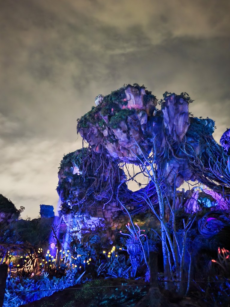 floating mountains pandora An image of the floating mountains at Pandora. There are two rocks covered in vines and plants, lit up in purple. The sky is grey behind it. There are yellow lights at the bottom of the image.