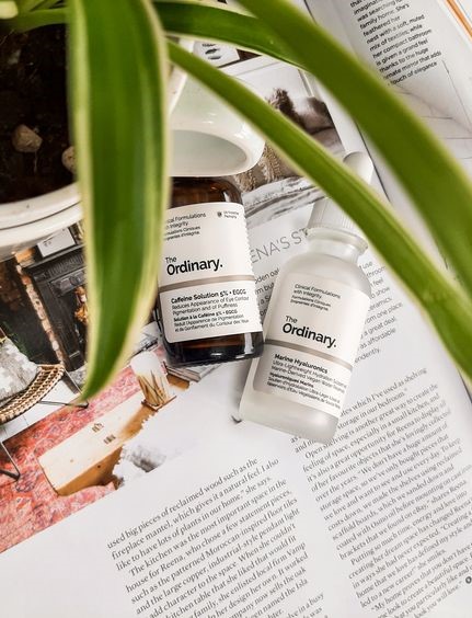 A page of a magazine with an amber and a clear bottle on it. There is a plant leaning over the picture. 