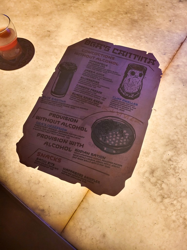 A backlit image of the Oga's Cantina menu on the lit up bar