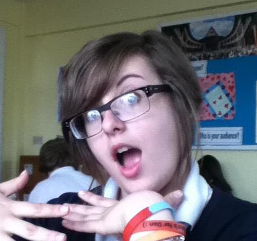 An image of a young, teenage Rosie, pulling a silly face at the camera. She has a sweeping brown fringe and large glasses.